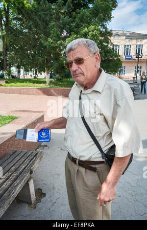 Elderly man showing his proof of participation in 2014 protests at Maidan Square in Kiev, photographed in Kolomyia, Ukraine Stock Photo