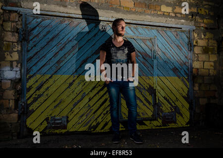 Ukraine, Kiev, Young man standing in front of garage with Ukrainian flag painted on door Stock Photo