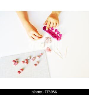 Cropped view of child's hands crafting clay beads Stock Photo