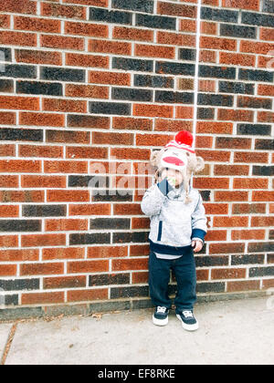 Boy leaning against brick wall Stock Photo