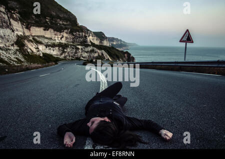 Woman lying in middle of road Stock Photo