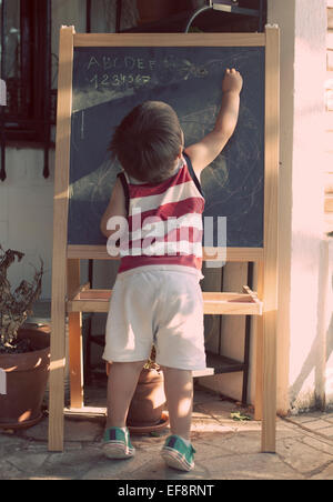 Boy writing on blackboard Stock Photo