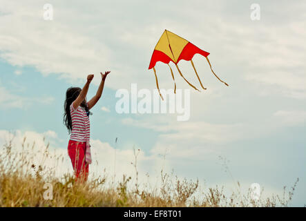 Portrait of girl (8-9) flying kite on hill Stock Photo