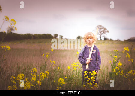 Boy with wooden sword standing in field Stock Photo