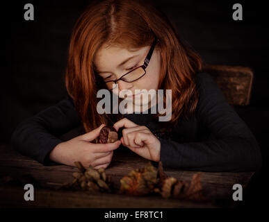 Girl watching leaves, cankers and horse chestnuts in autumn Stock Photo