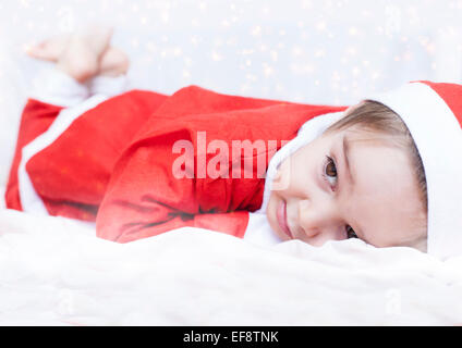 Boy dressed as Santa Claus lying on bed Stock Photo