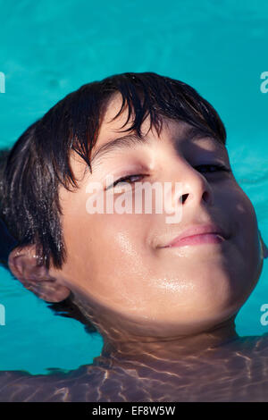 Close-up of a smiling boy floating on his back in a swimming pool Stock Photo