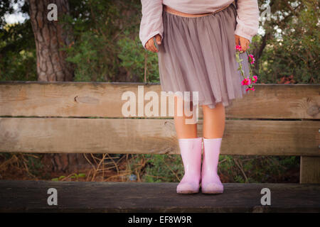 Girl standing on a wooden bench holding a floral wreath Stock Photo
