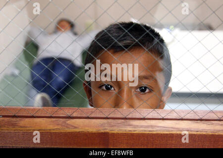 A young Mexican boy looks out from a detention center room after being intercepted illegally crossing the U.S. border June 5, 2014 in Brownsville, Texas. Stock Photo