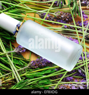 a bottle with fresh cologne and a pile of lavender flowers Stock Photo