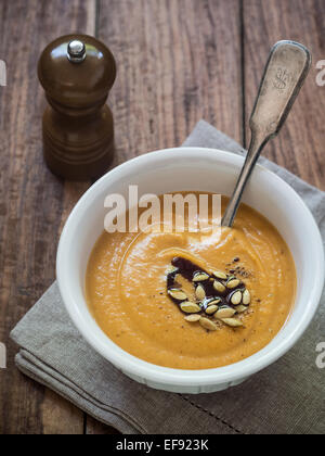 Vegan pumpkin cream soup with coconut cream, served with pumpkin seeds and pumpkin seed oil. Stock Photo