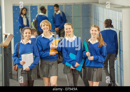 Portrait of smiling female students wearing school uniforms walking through school corridor Stock Photo