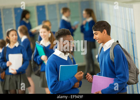 Two male students wearing school uniforms talking in locker room Stock Photo
