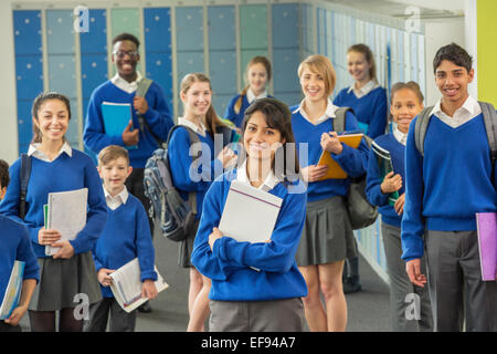 Group portrait of schoolchildren wearing school uniforms standing in corridor and smiling Stock Photo