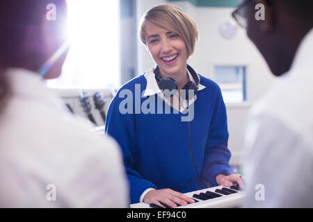 Smiling students playing synthesizer in classroom Stock Photo