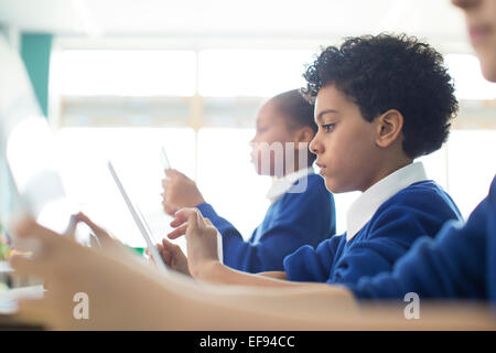 Schoolboys and schoolgirls sitting in classroom using tablet pc's Stock Photo