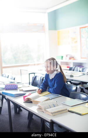 Female pupil sitting in classroom with tablet pc Stock Photo