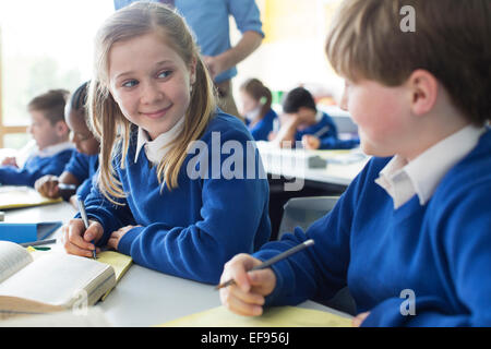 Schoolgirl and schoolboy learning in classroom Stock Photo