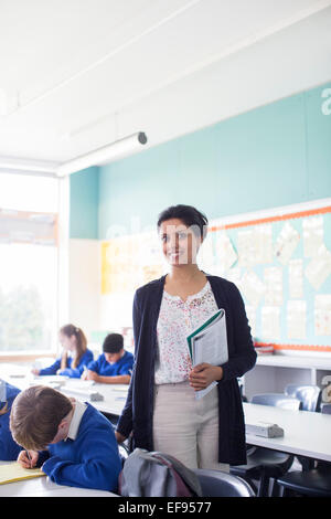 Portrait of smiling female teacher and elementary school children in classroom Stock Photo