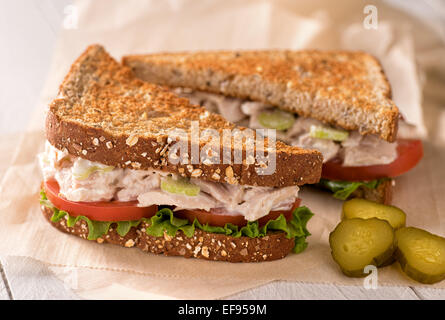 A delicious flaked white tuna salad sandwich with tomato, lettuce, mayonnaise, and pickles. Stock Photo