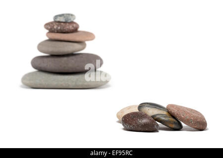 Stone cairn made from a variety of colorful rocks.  Four extra stones in foreground are in sharp focus. Cairn is in soft focus. Stock Photo