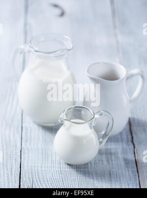 Three milk jars on white wooden background Stock Photo