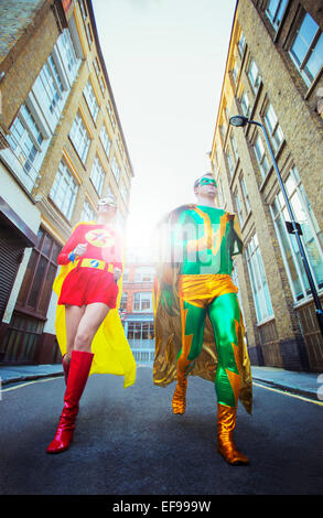 Low angle view of superhero couple running on city street Stock Photo