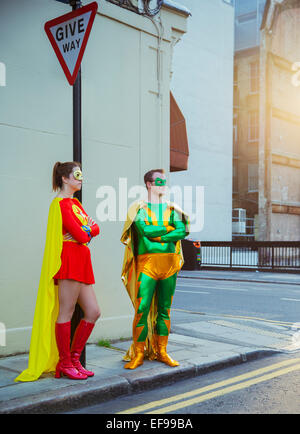 Superhero couple waiting at corner on city sidewalk Stock Photo