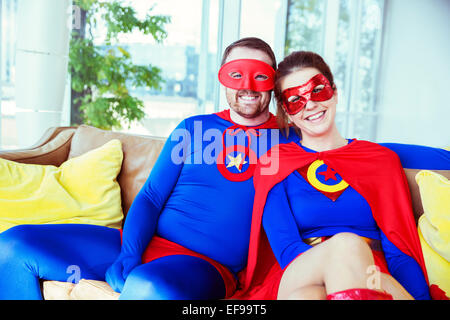 Superhero couple smiling on living room sofa Stock Photo