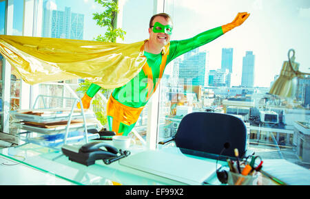 Superhero flying in office Stock Photo