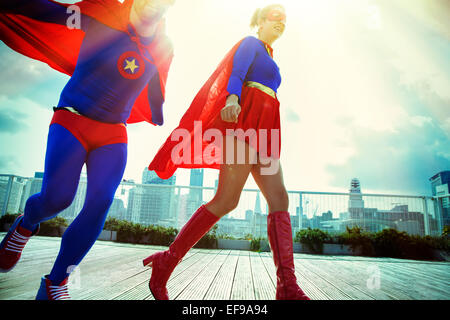 Superheroes running on city rooftop Stock Photo