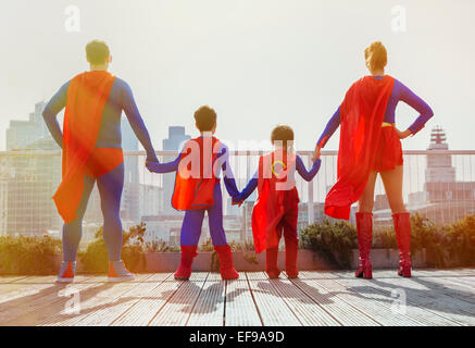 Superhero family standing on city rooftop Stock Photo