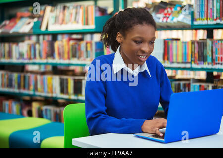 Busy female student with laptop in library Stock Photo