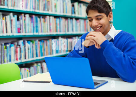 Portrait of student smiling and looking at laptop in library Stock Photo