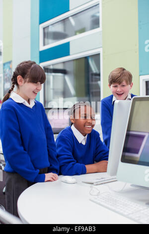 Primary school children looking at computer and smiling Stock Photo