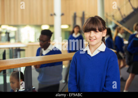 Portrait of smiling elementary school girl wearing blue school uniform standing in school corridor Stock Photo