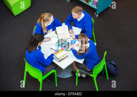 Overhead view of four students doing their homework at round table Stock Photo