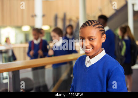 Portrait of smiling elementary school girl wearing blue school uniform standing in school corridor Stock Photo