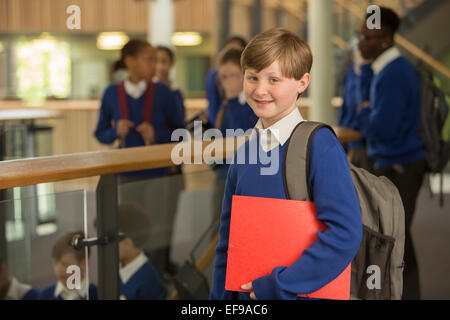 Portrait of elementary school boy wearing blue school uniform standing in school corridor Stock Photo