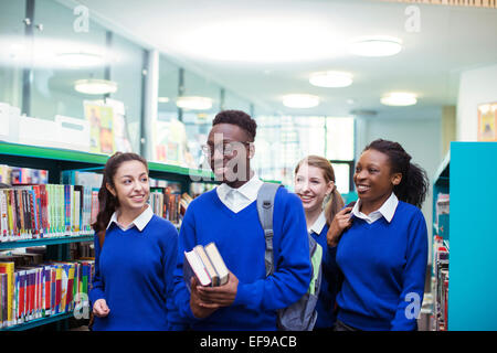 Cheerful students wearing blue school uniforms walking through library Stock Photo