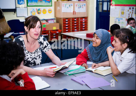 Smiling teacher with happy students in primary school classroom UK Stock Photo
