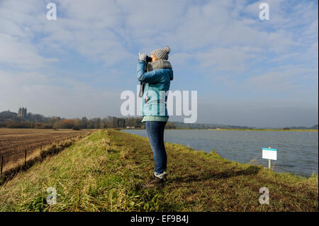 Woman birdwatching with binoculars on the banks of the River Adur at Shoreham UK Stock Photo