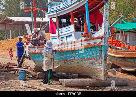 Men working in wooden boats with old oil barrels in the 