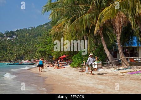 Beach vendor selling fruit and Western tourists sunbathing on the island Ko Tao / Koh Tao, Chumphon Archipelago, Thailand Stock Photo