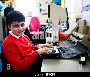 Blind boy using braille machine in Special Needs class in London Primary school Stock Photo