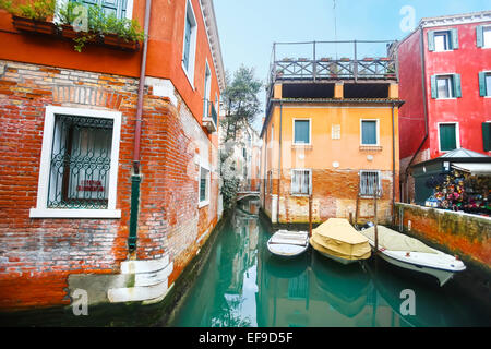 A view of empty boats parked next to buildings in a water canal in Venice, Italy. Stock Photo