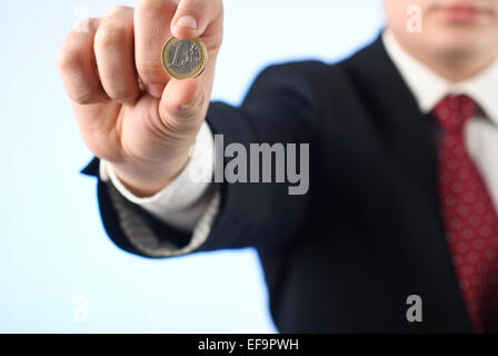 Young businessman in suit holding one Euro coin Stock Photo