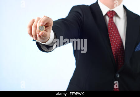 Young businessman in suit holding one Euro coin Stock Photo