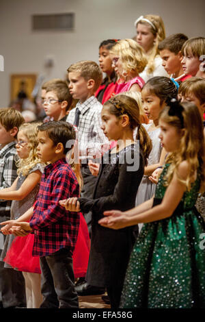 Multiracial young children gesture as they sing carols during Christmas mass at St. Timothy's Catholic Church, Laguna Niguel, CA. Stock Photo