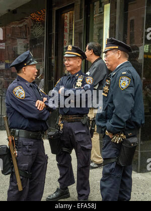 Three senior Chinese American policemen talk on a street corner in New York City's Chinatown. Note long service medals. Stock Photo